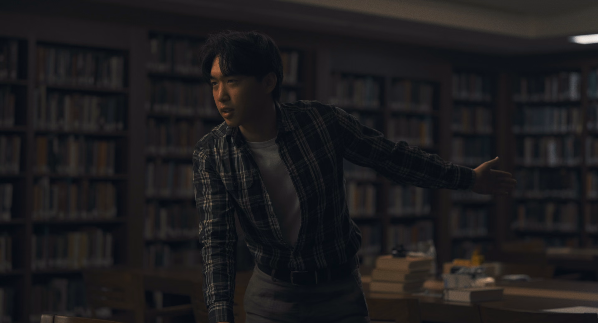 A researcher in a plaid shirt leans across a table in a library
